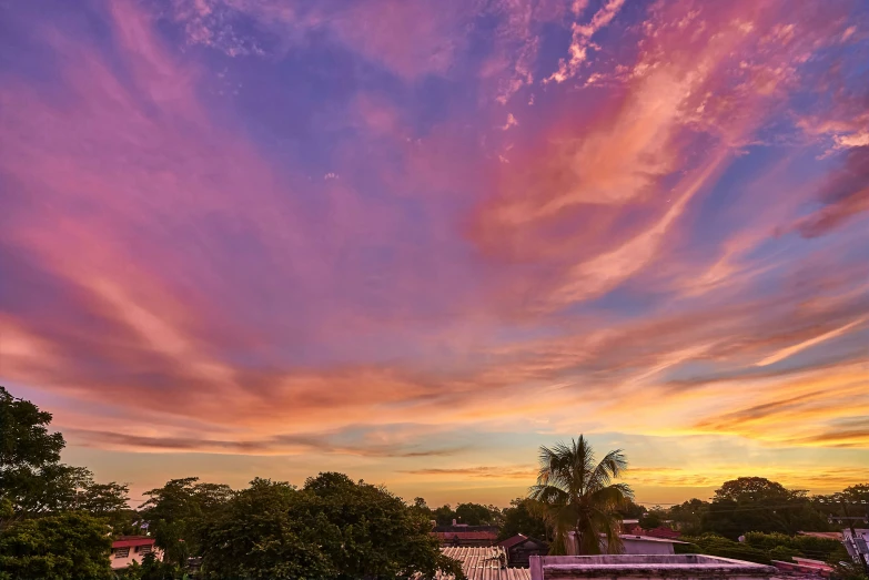 a clock tower and buildings underneath a beautiful sunset