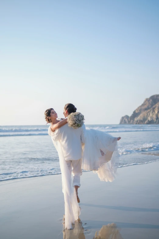 two beautiful young women standing on top of a sandy beach