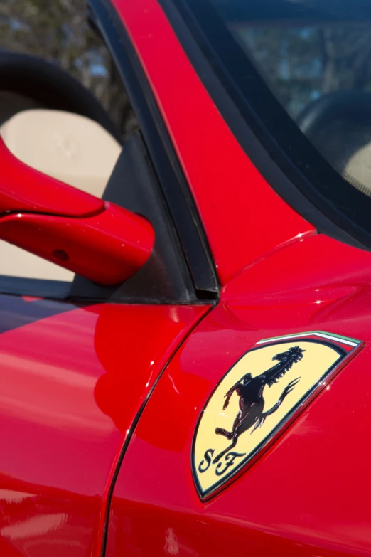 the side mirror of a red car showing a logo