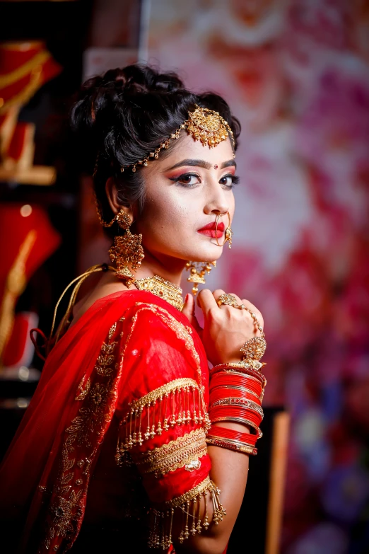 a woman in red indian wedding dress with makeup on