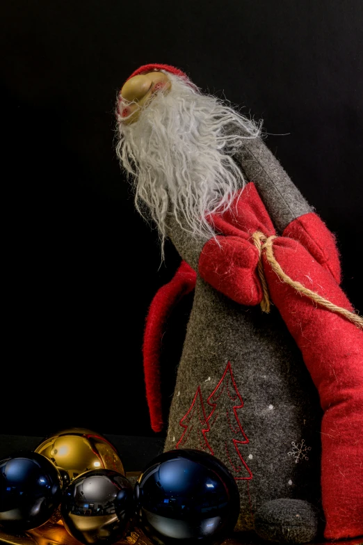 a gnome like figurine sitting on a table with three ornaments