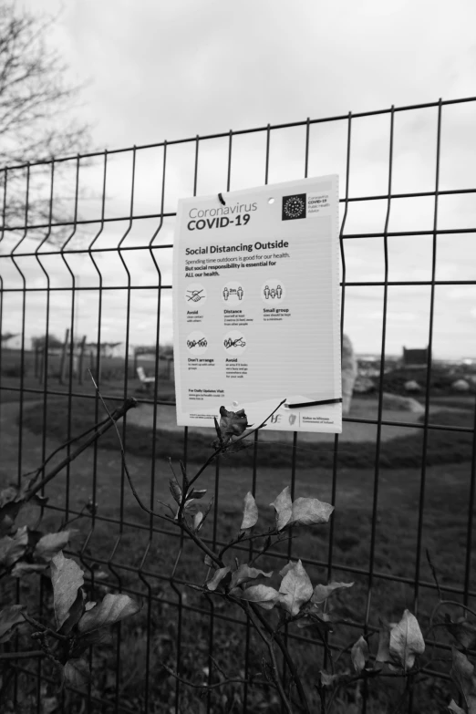 a sign posted on a fence behind a barbed wire fence