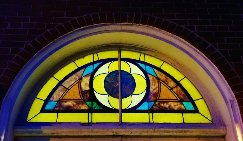 an arched glass window is lit by the sun in the stained glass