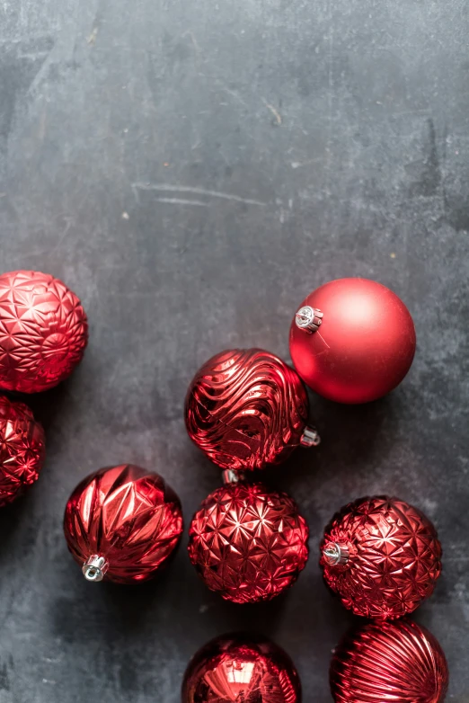 christmas ornaments sit on a black surface next to some shiny glass balls