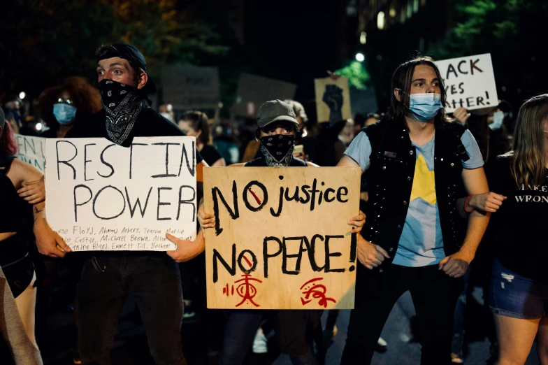 a crowd of people holding signs and wearing masks