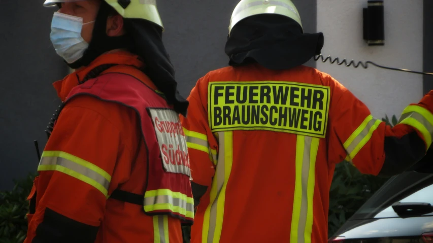 two people in orange safety wear with masks