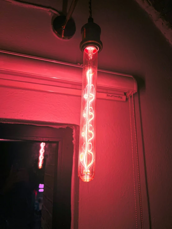 a red light hanging in the dark from a ceiling