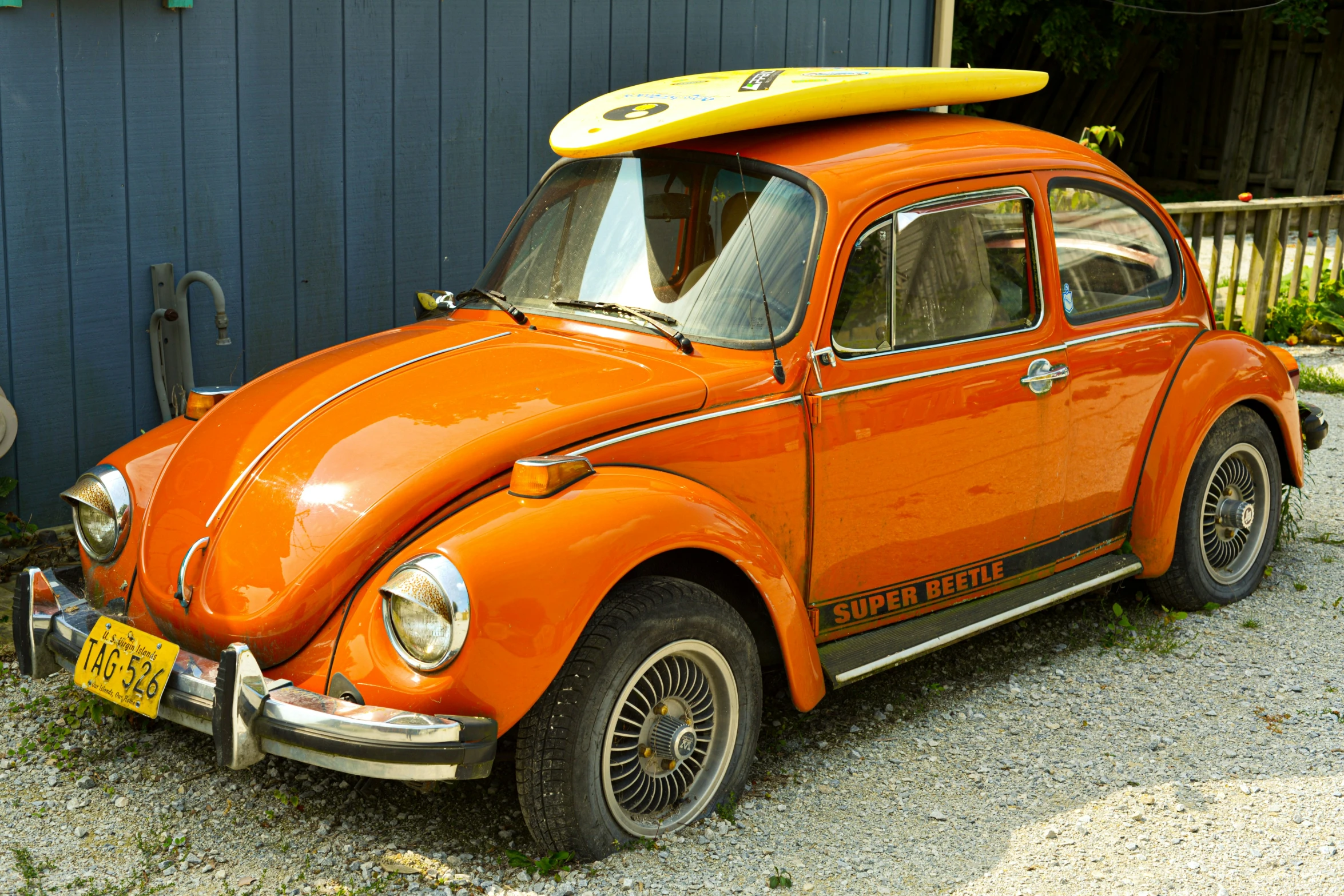 a orange car with a yellow surfboard on top of it's roof