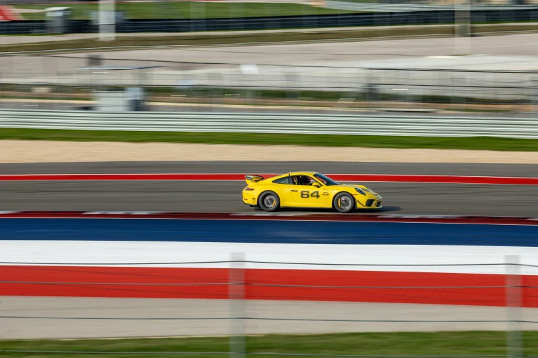 yellow car racing down the track near the curve