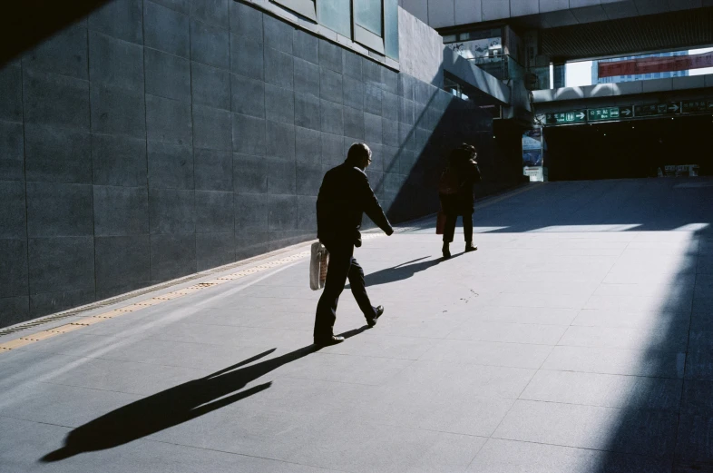 two men walking down the street with their shadows cast on them