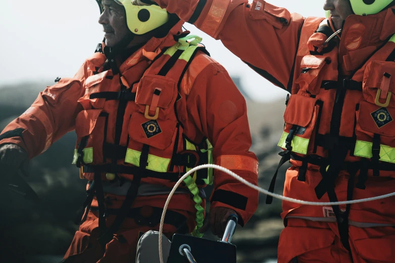 two men wearing safety gear stand on top of a rock