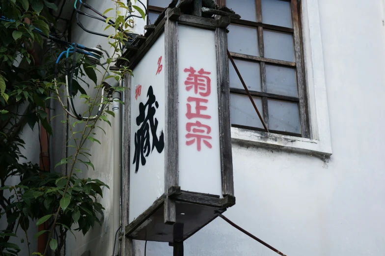 a light with oriental writing hangs on the outside wall of a building