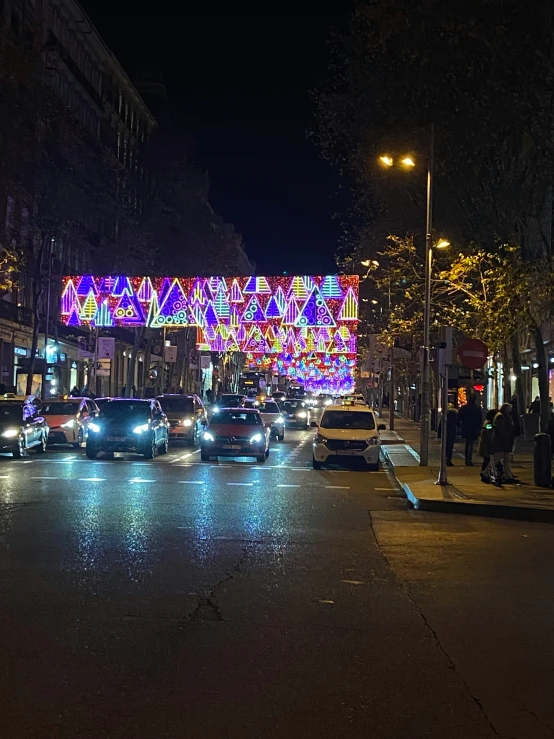 the cars are driving down the city street at night