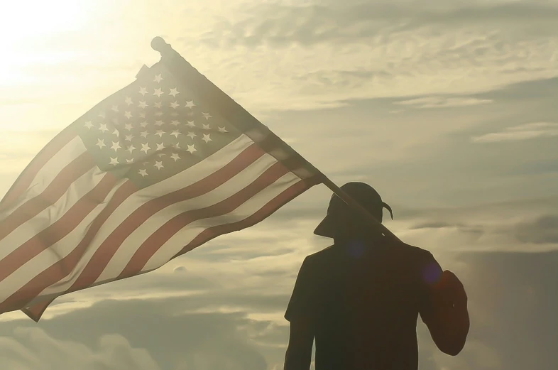 a silhouetted person holding an american flag