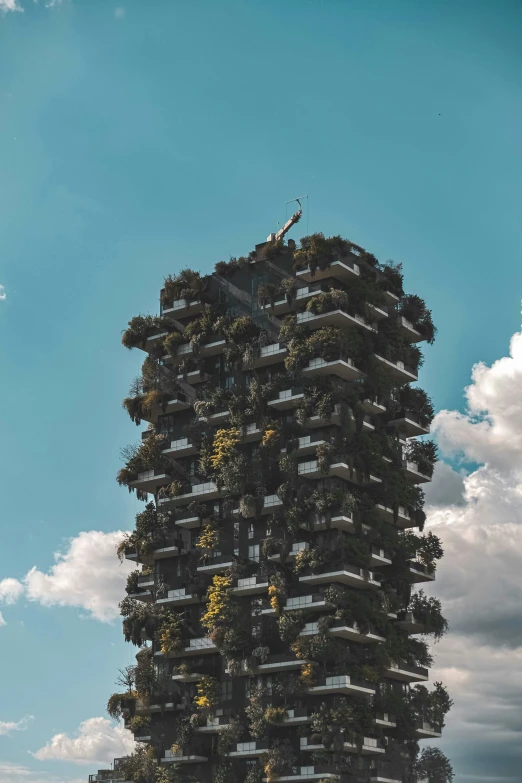 a tall building with plant filled balconies on it