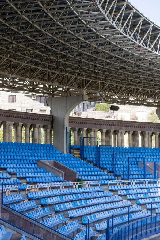 rows of blue stadium seats are against an open roof