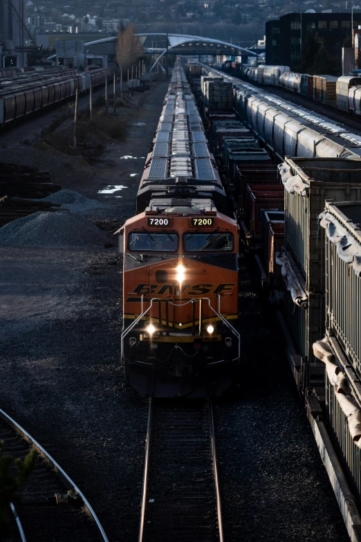 an orange and yellow train traveling past a train station