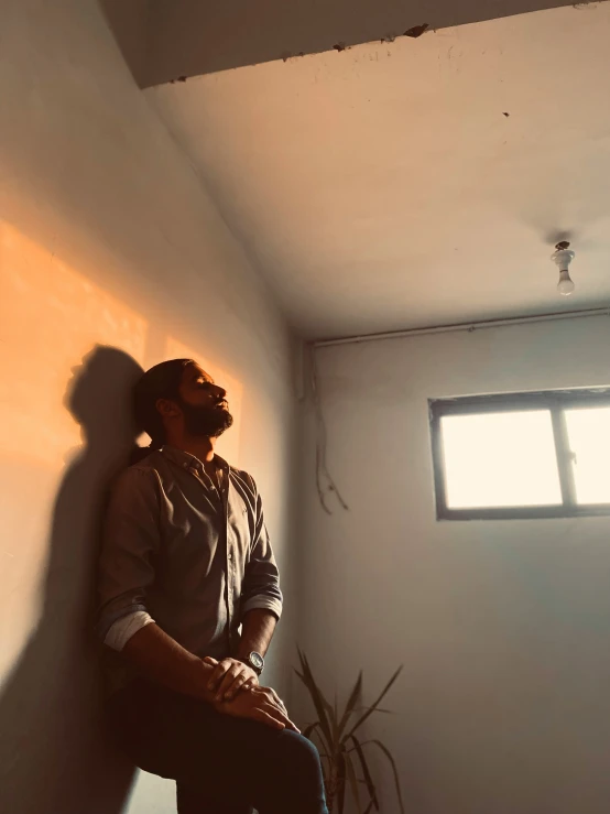 man sitting on ledge in corner of room