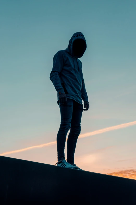 man standing on the edge of a wall at sunset