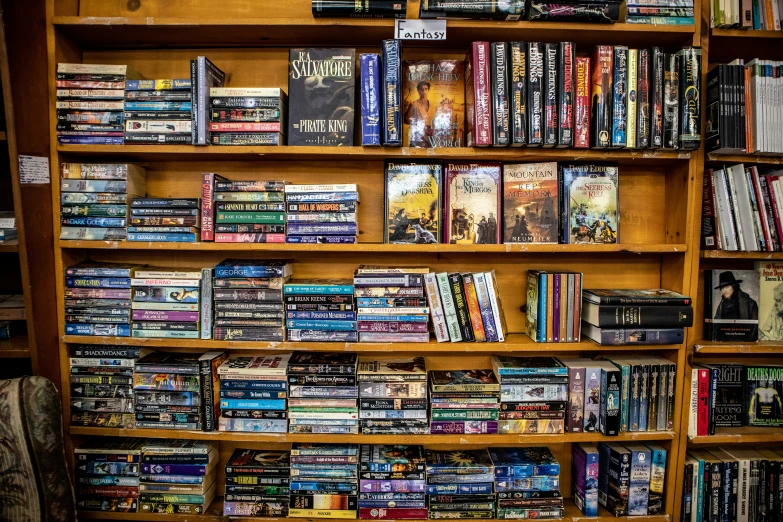 a very tall wooden book shelf full of different kinds of movies