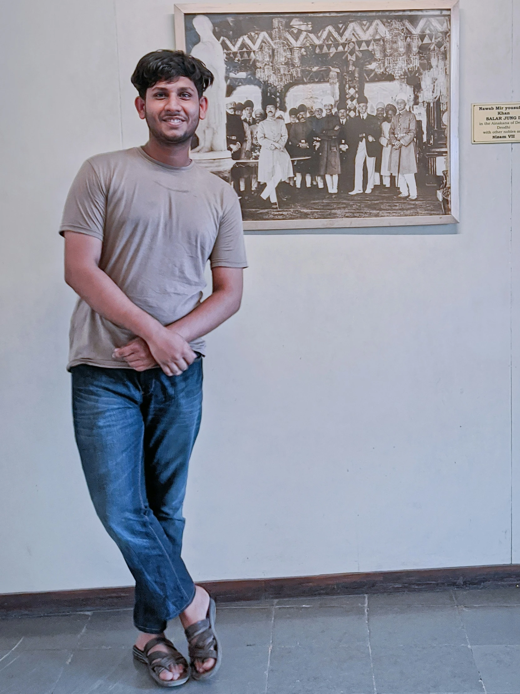 the man is posing in front of a portrait of men and women