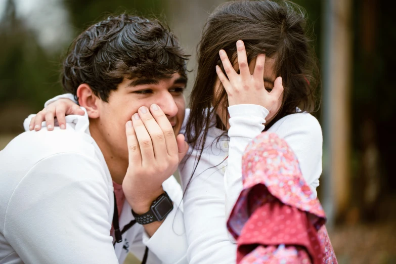 young man and woman holding their hands to their mouths