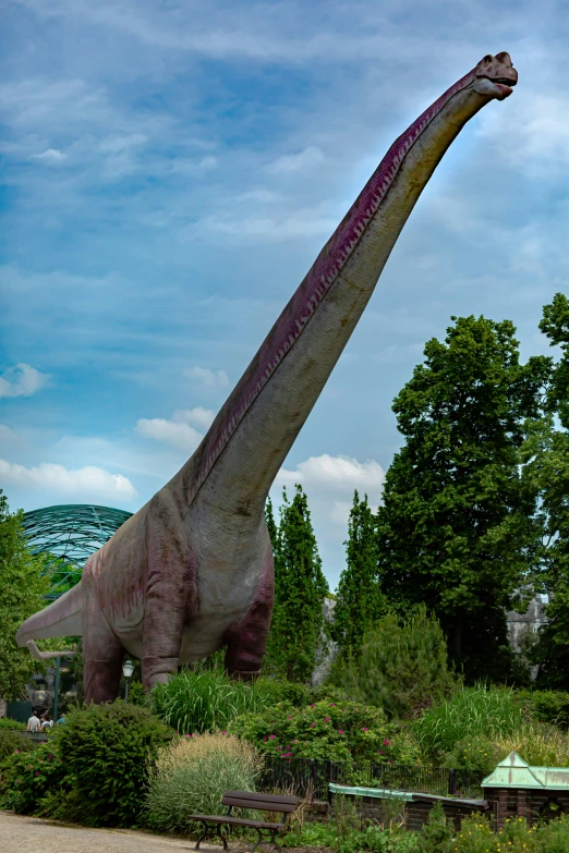 a giant dinosaur statue standing near trees