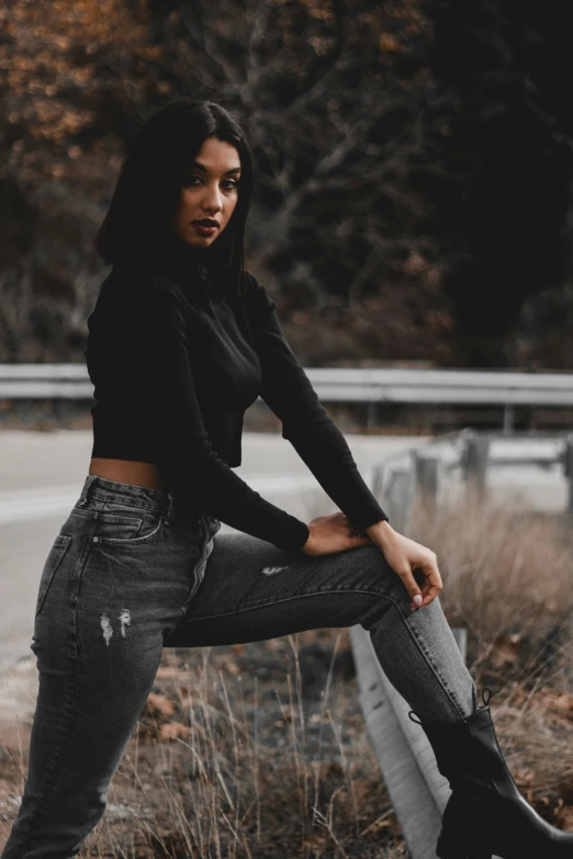 a young woman is posing by a road