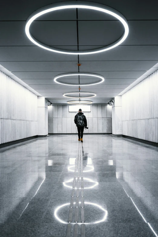 a man in a hooded jacket walks in the white tunnel