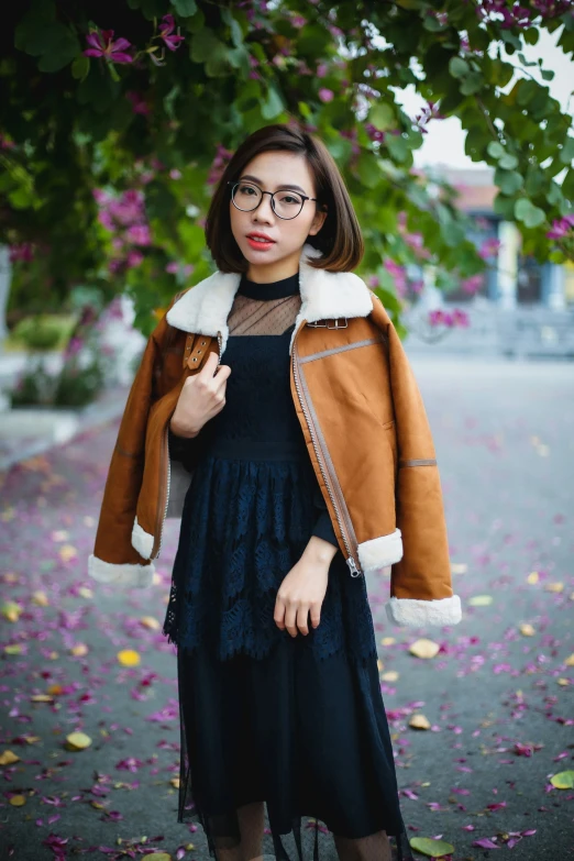 a girl in black dress posing by some flowers