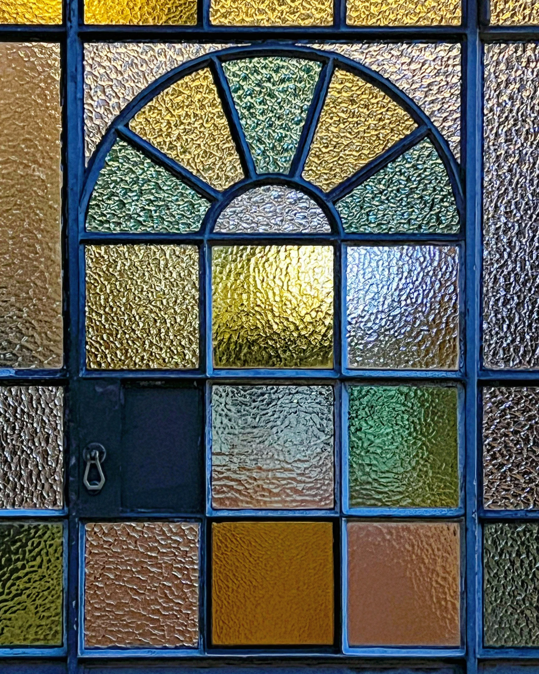 an arched glass window with multi - colored glass