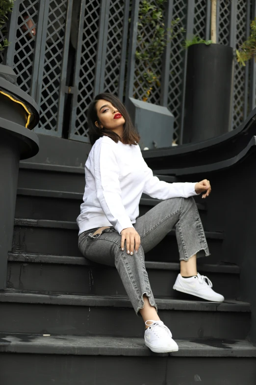 a girl sitting on a set of steps with white sneakers