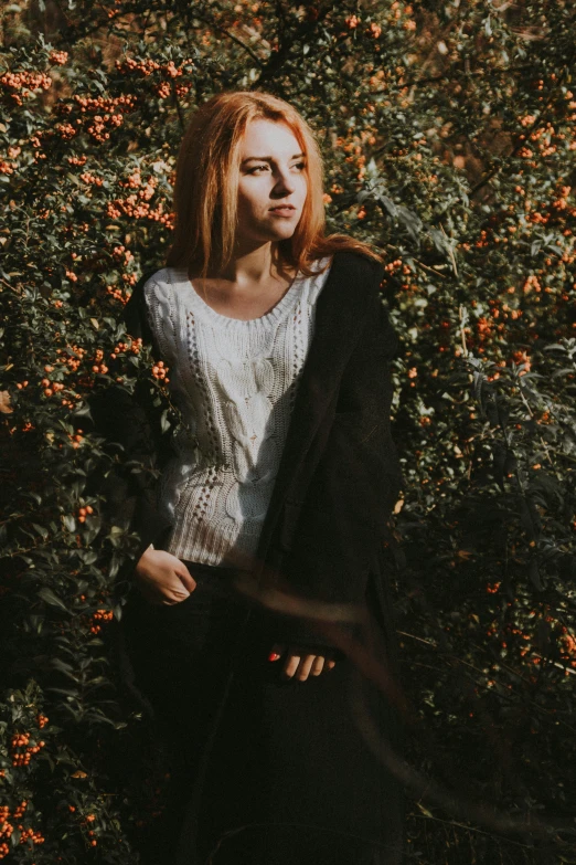 a woman standing in front of some bushes