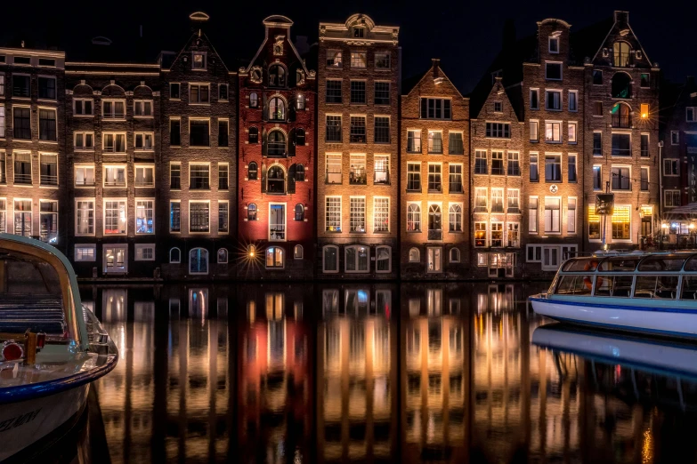 boats parked along the side of a canal at night