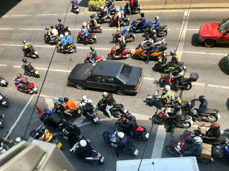 a large group of motorcyclists gather around in a parking lot