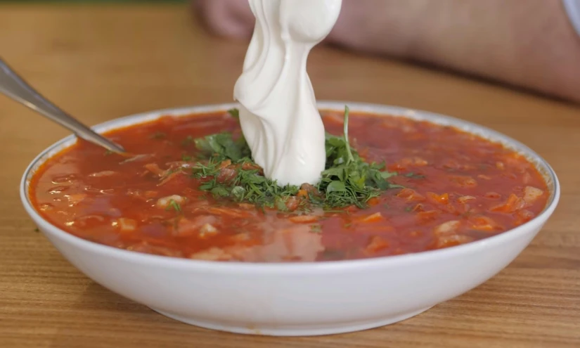 a person reaching for the top of a bowl of soup