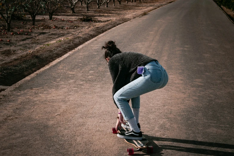 a girl is riding a skateboard down a road