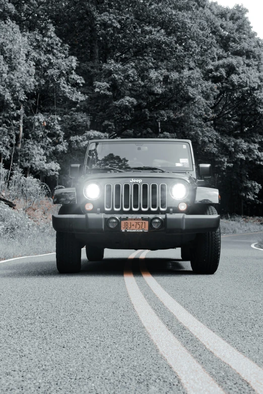 black jeep with headlights on driving on the road