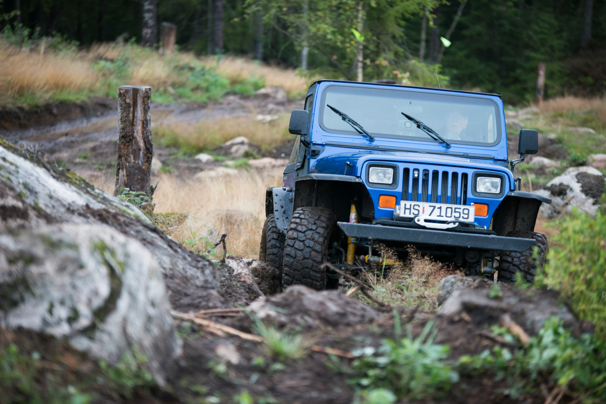 the blue jeep is parked in the mud