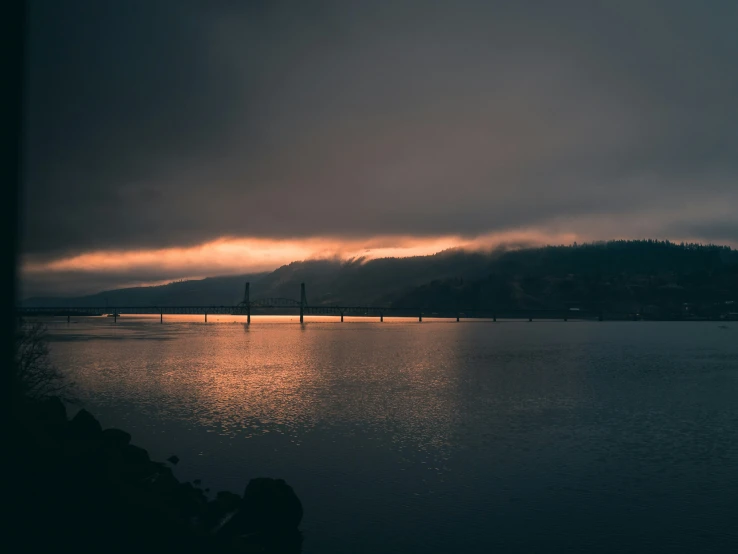 a beautiful sunset and some dark clouds reflect off the water