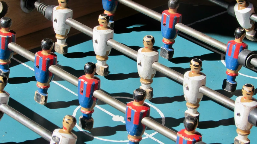 foosball table with wooden dolls in blue and red uniform