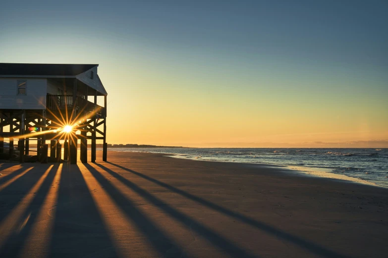 the sun shines on a building with a balcony by the beach