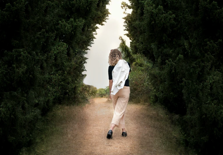 a woman is walking down a dirt path