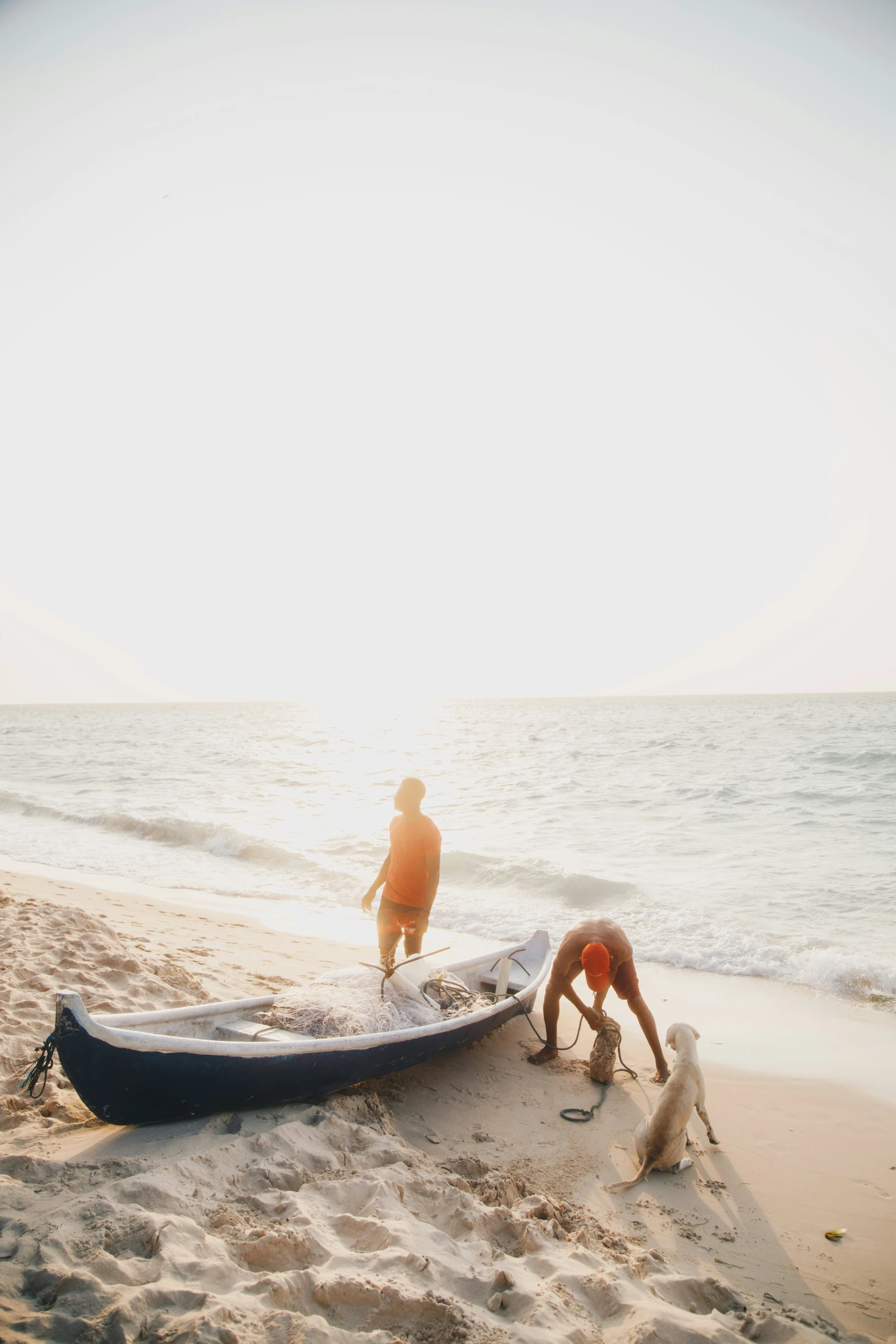 two people on the beach hing a small boat