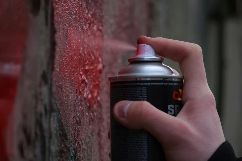 a hand holding onto a can of soda on a brick wall