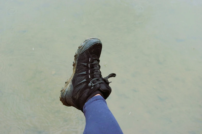 someone standing in the water wearing muddy boots