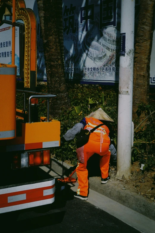 two workers wearing orange overalls are on a road