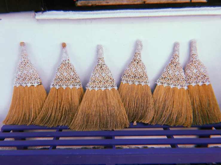 several pairs of yellow handmade brooms on display