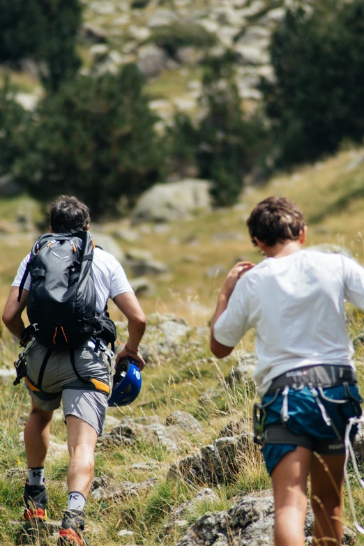 a man in a white shirt is walking along a rocky hill