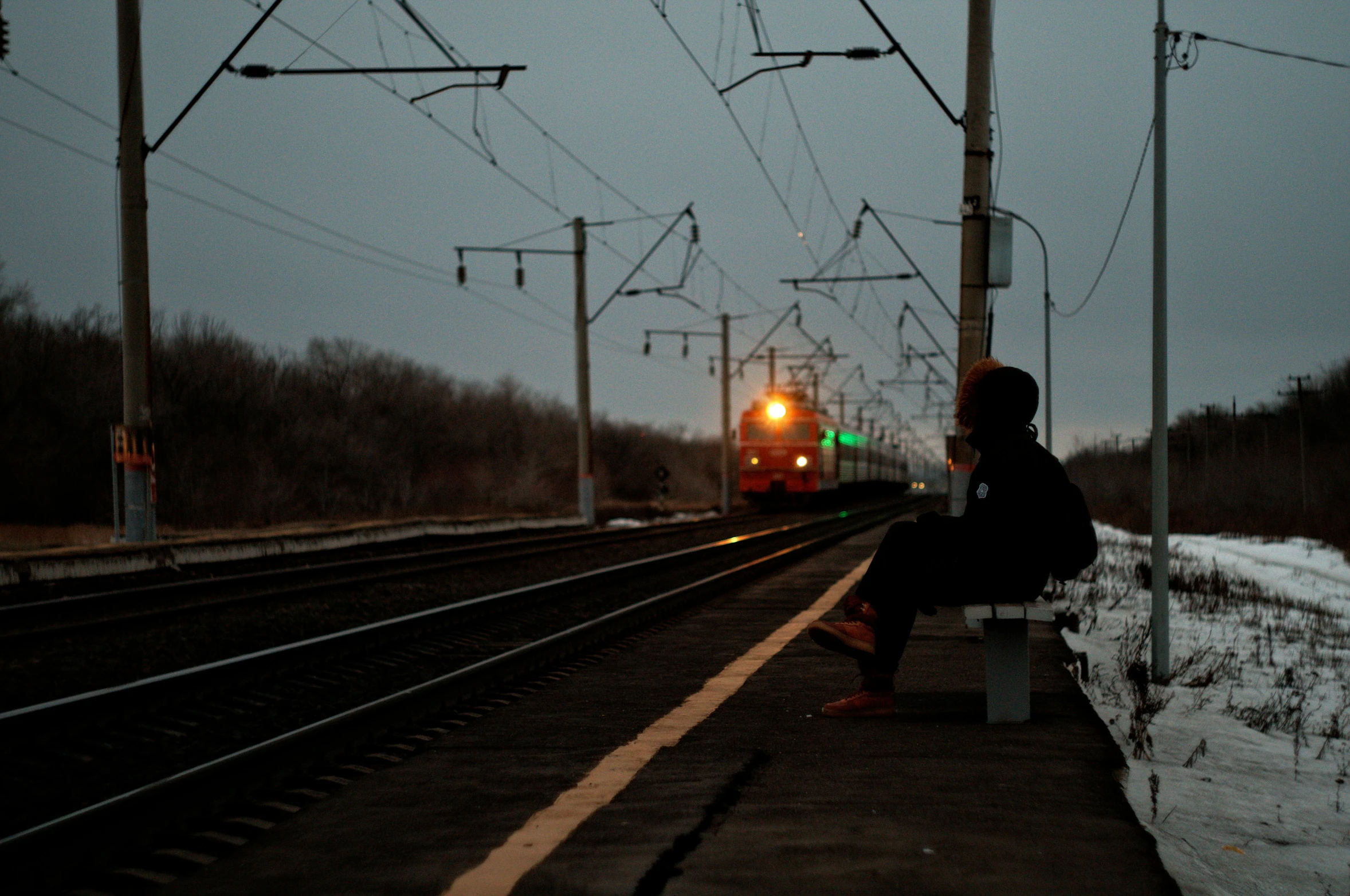 a man sitting on the bench watching train go by
